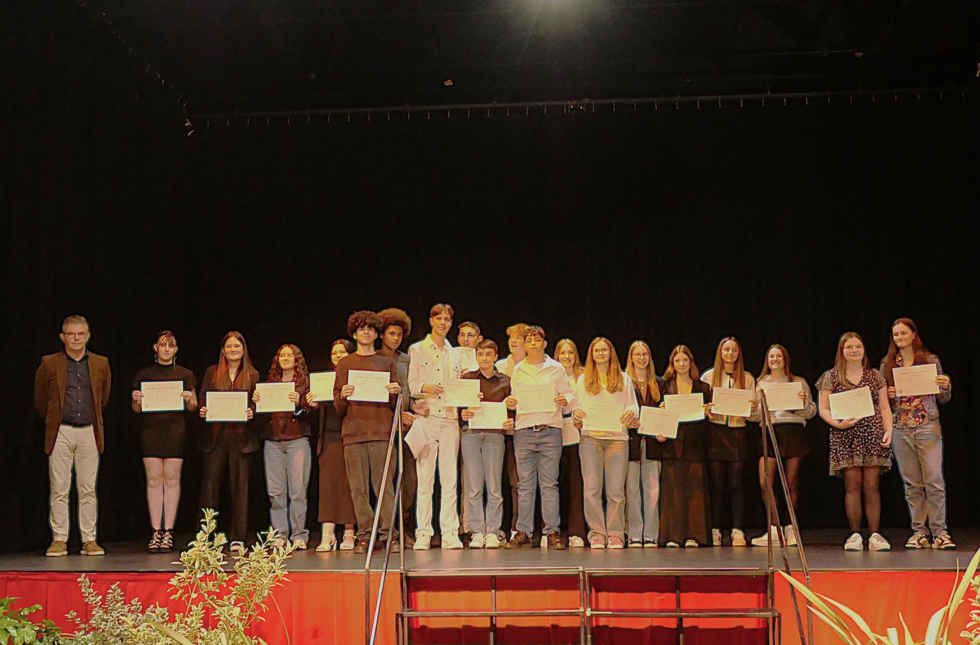 Des personnes sur une scène qui tiennent des feuilles en papier