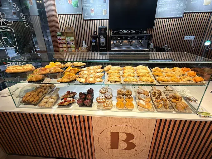 Vitrina llena de pasteles y productos horneados en una cafetería con la letra 