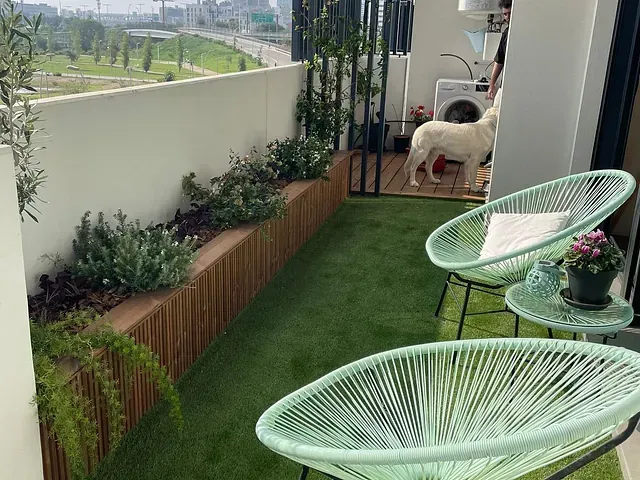 Un perro está parado en un balcón al lado de dos sillas y una mesa.