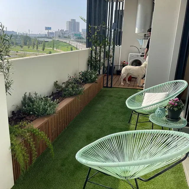 Un perro está sentado en un balcón con dos sillas y una mesa.