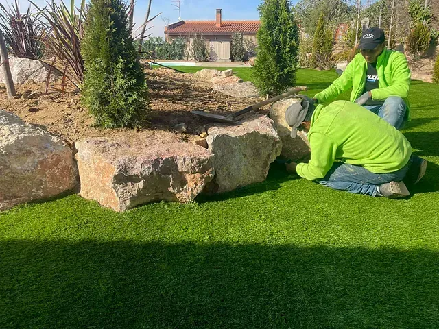 Dos hombres están trabajando en un exuberante césped verde.
