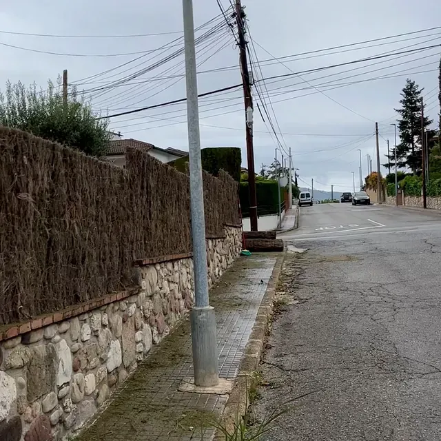Una calle con un muro de piedra y un poste de teléfono