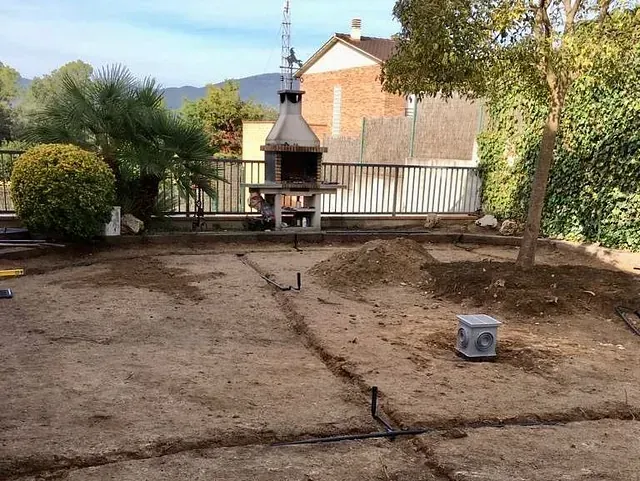 Un patio trasero con parrilla y un montón de tierra.