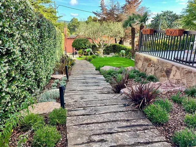 Una pasarela de madera en un jardín rodeado de plantas y árboles.