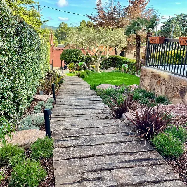 Una pasarela de madera que conduce a un exuberante jardín verde.