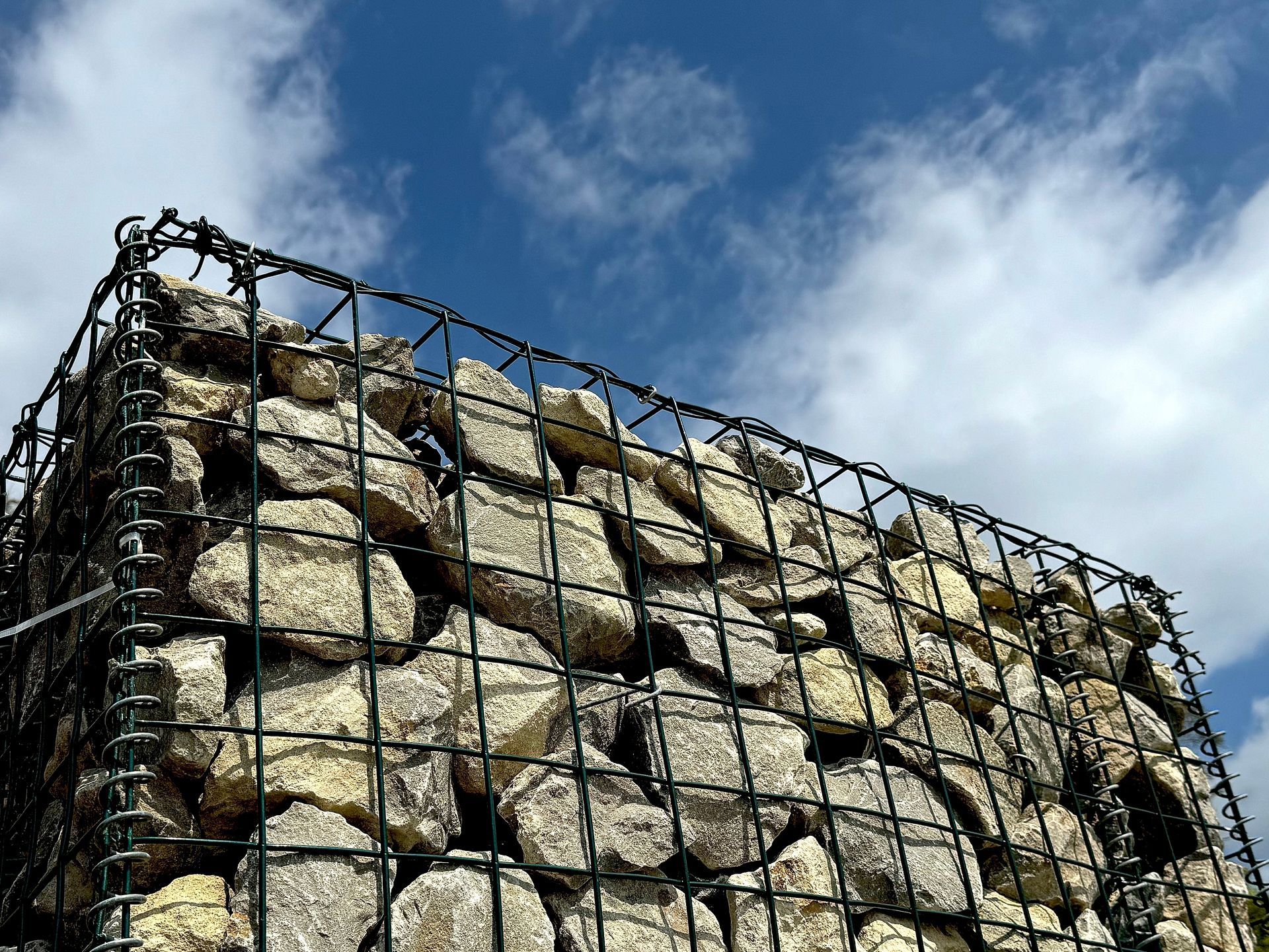 Das dunkelgraue Einfahrtstor ist geöffnet und gibt den Blick auf eine Kiesauffahrt frei, die zu einer Holzgarage führt.