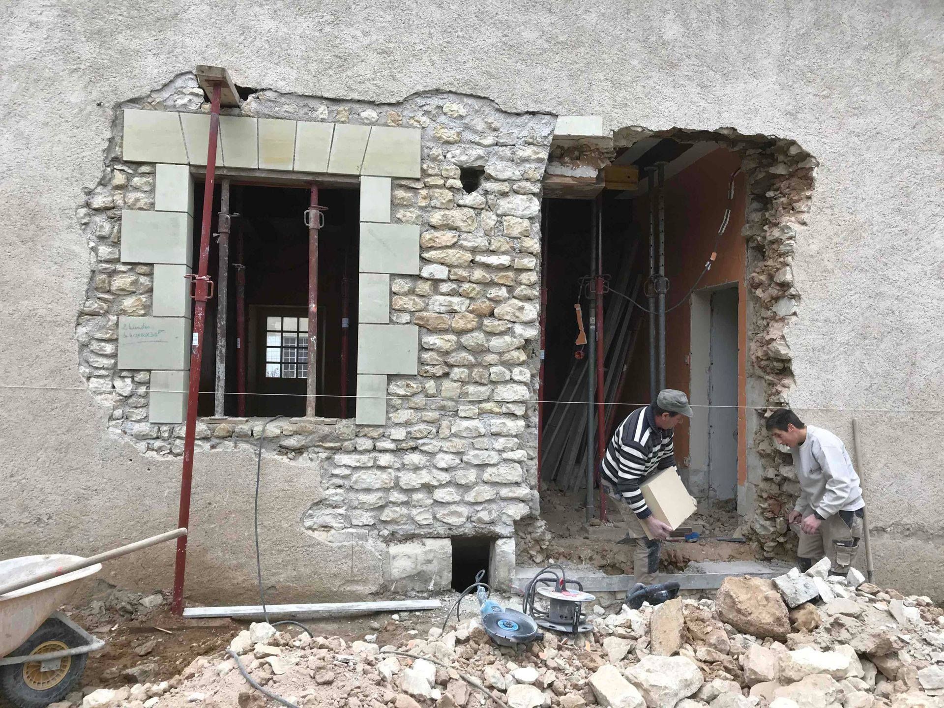 Ouvriers réalisant des ouvertures dans un mur en pierre