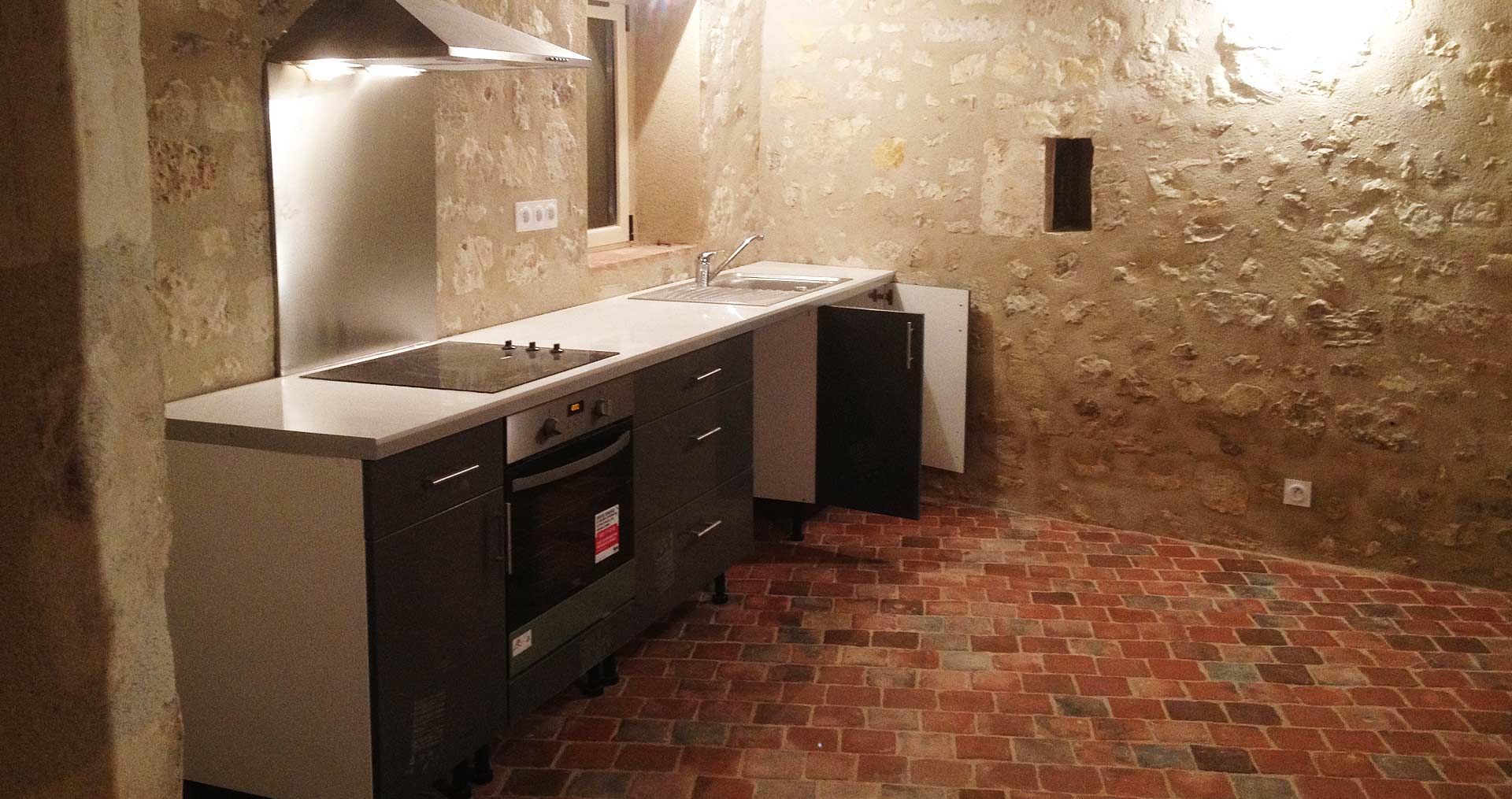 Cuisine neuve avec meubles gris et au sol en tommettes anciennes