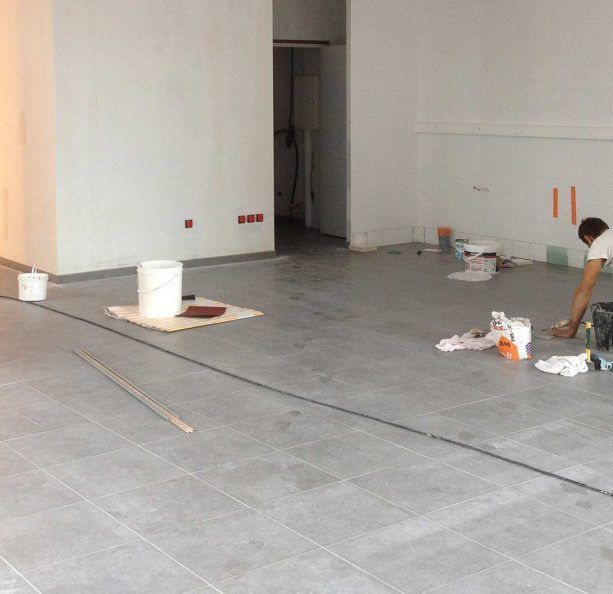Ouvrier posant un sol en carrelage gris
