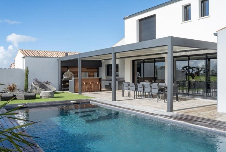 Piscine en premier plan avec pergolas et table à manger.
