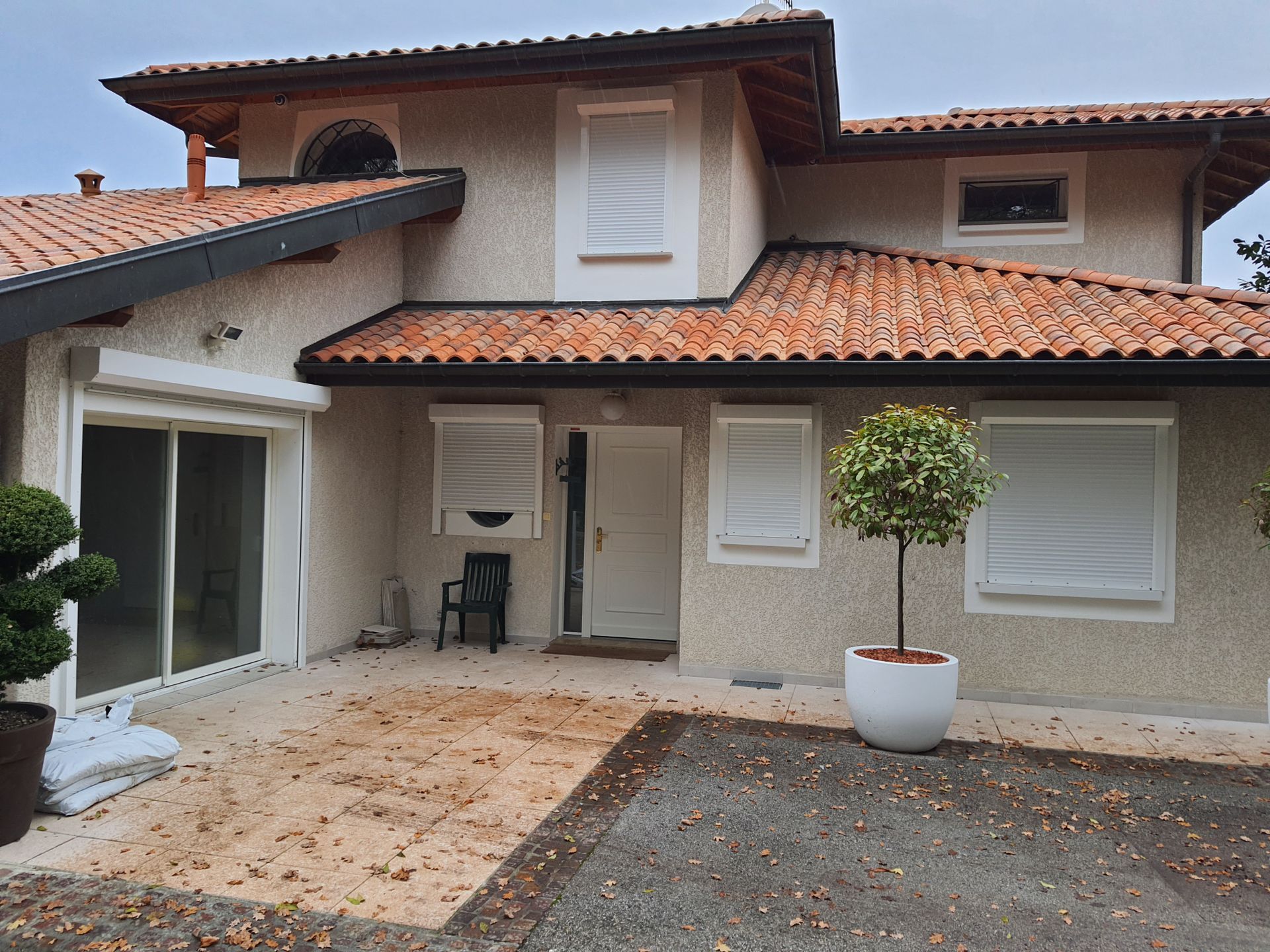 Une maison avec une toiture en tuile et des menuiseries blanches en PVC.