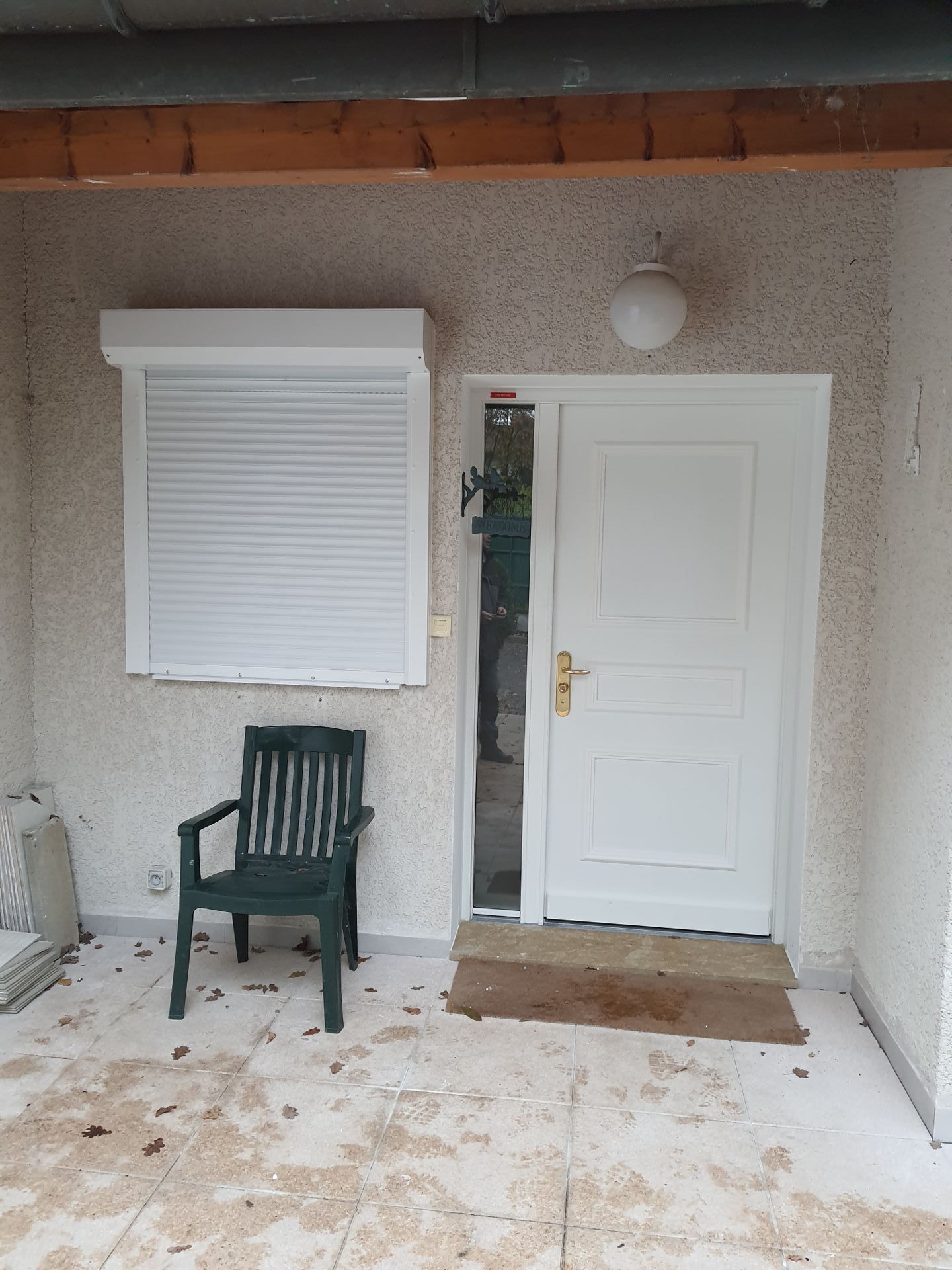 Entrée extérieure d'une maison avec menuiseries blanches.