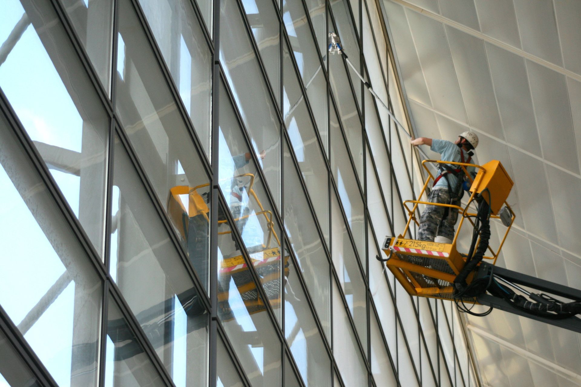 Homme qui nettoie des vitres en hauteur à l'aide d'une nacelle