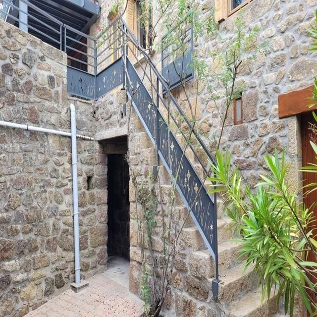 Extérieur en pierre avec escalier métallique.