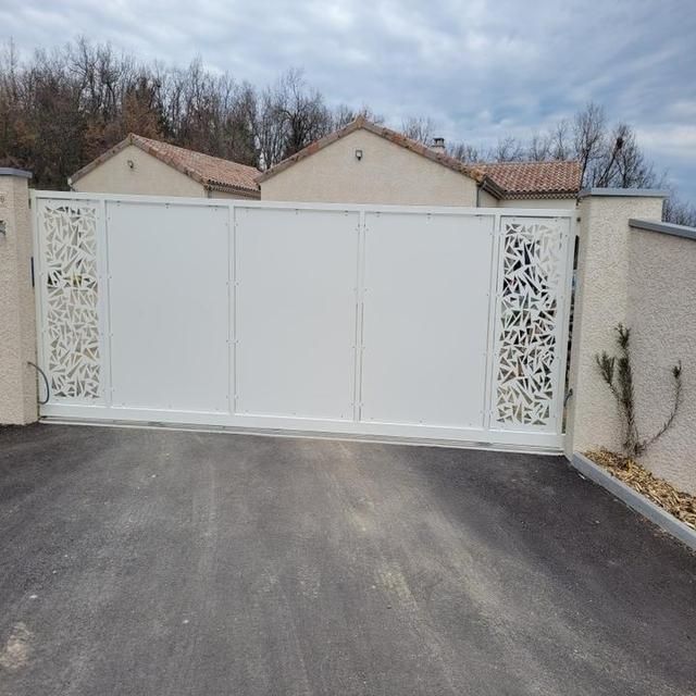 Portail coulissant blanc avec découpes décoratives.
