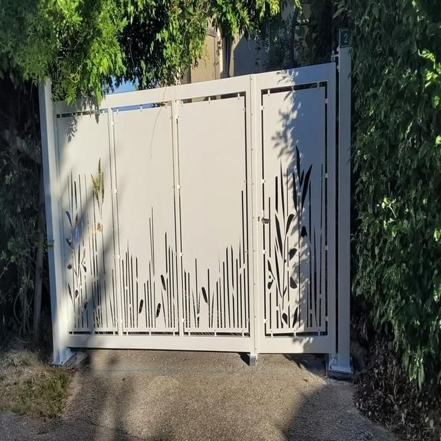 Portail en métal blanc avec motif découpé de roseaux et d'herbe.