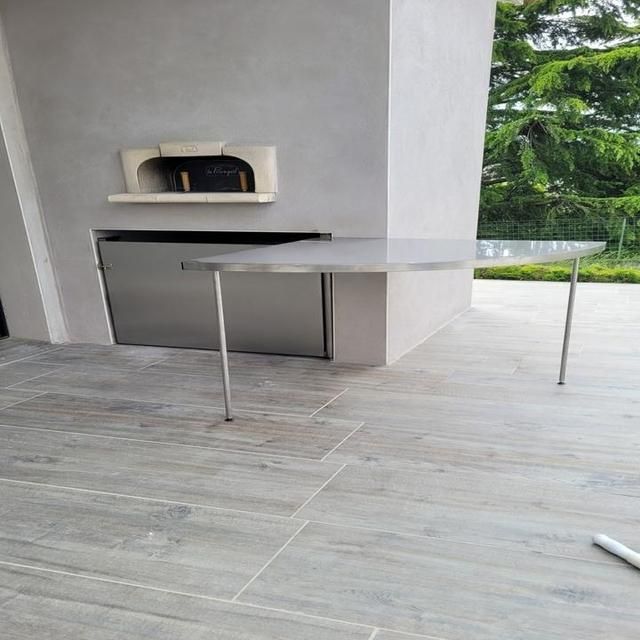 Four à pizza extérieur avec table en inox sur une terrasse carrelée.