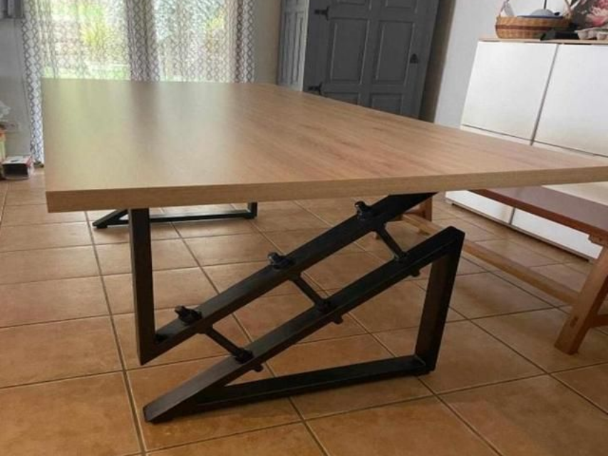 Table en bois avec pieds inclinés en métal noir dans une pièce avec une fenêtre et une porte.