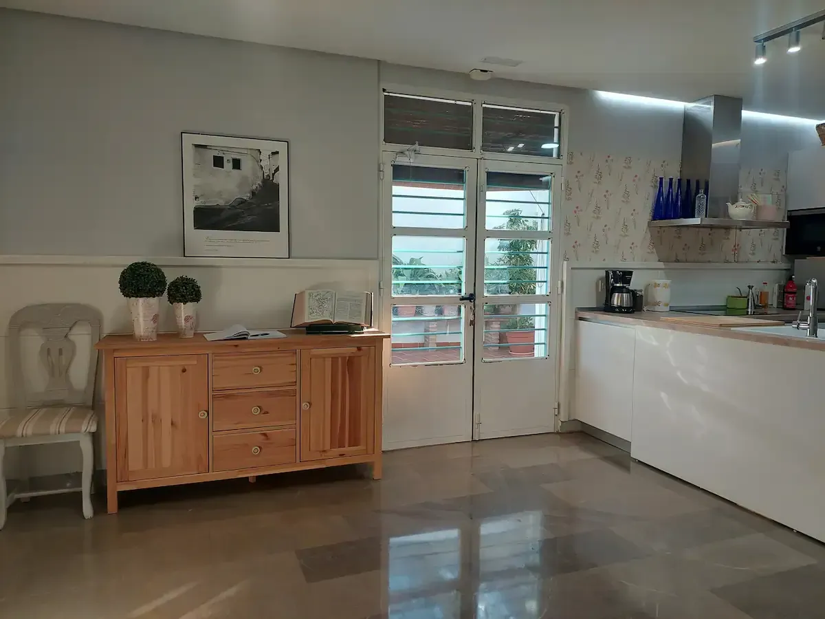 Una cocina con gabinetes blancos y una cómoda de madera.
