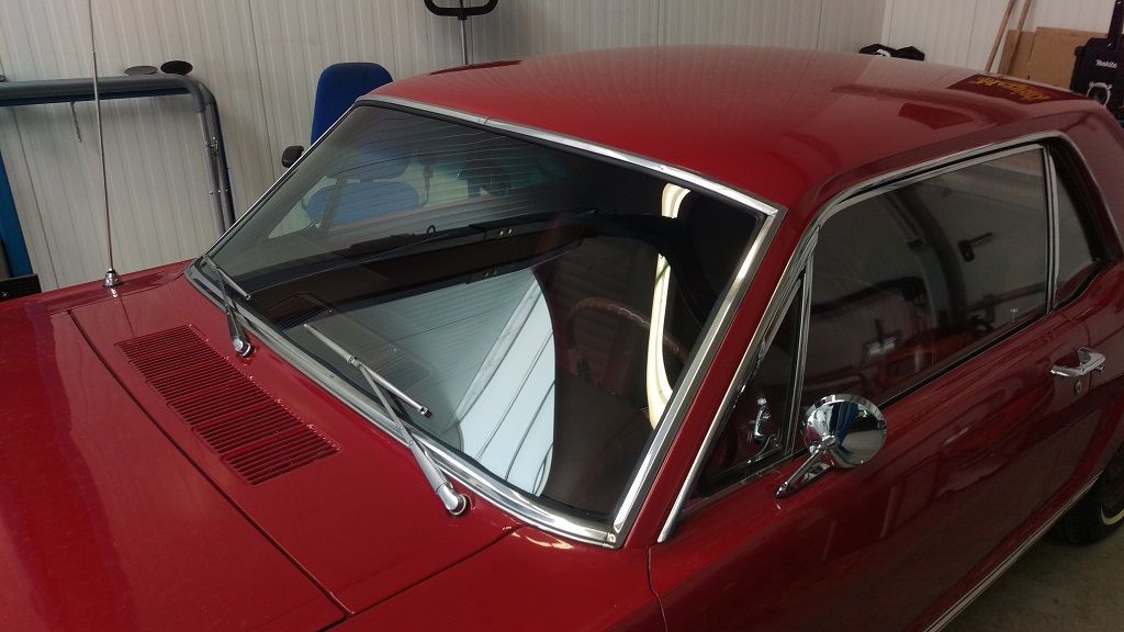 Ein rotes Auto steht mit geöffneter Motorhaube in einer Garage.