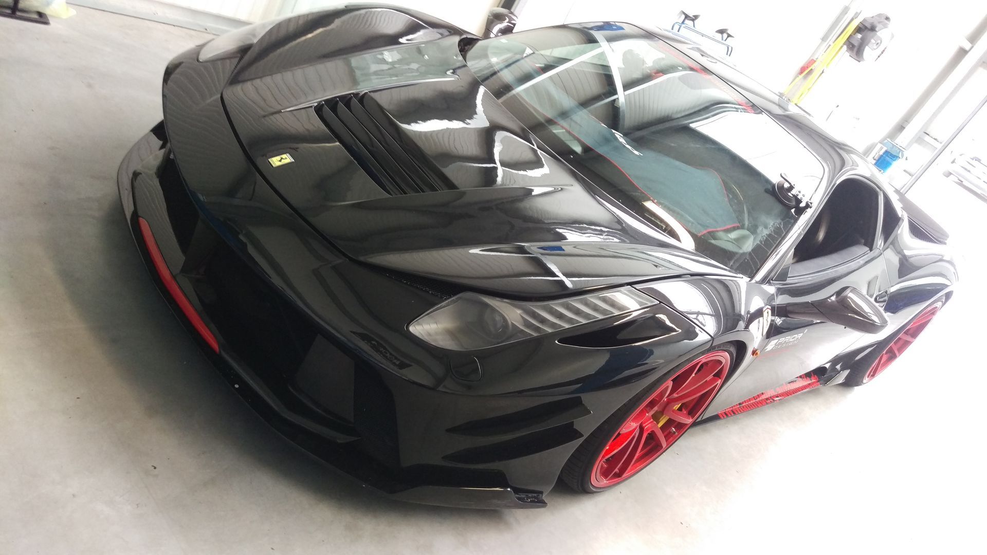 Ein schwarzer Sportwagen mit roten Rädern steht in einer Garage.