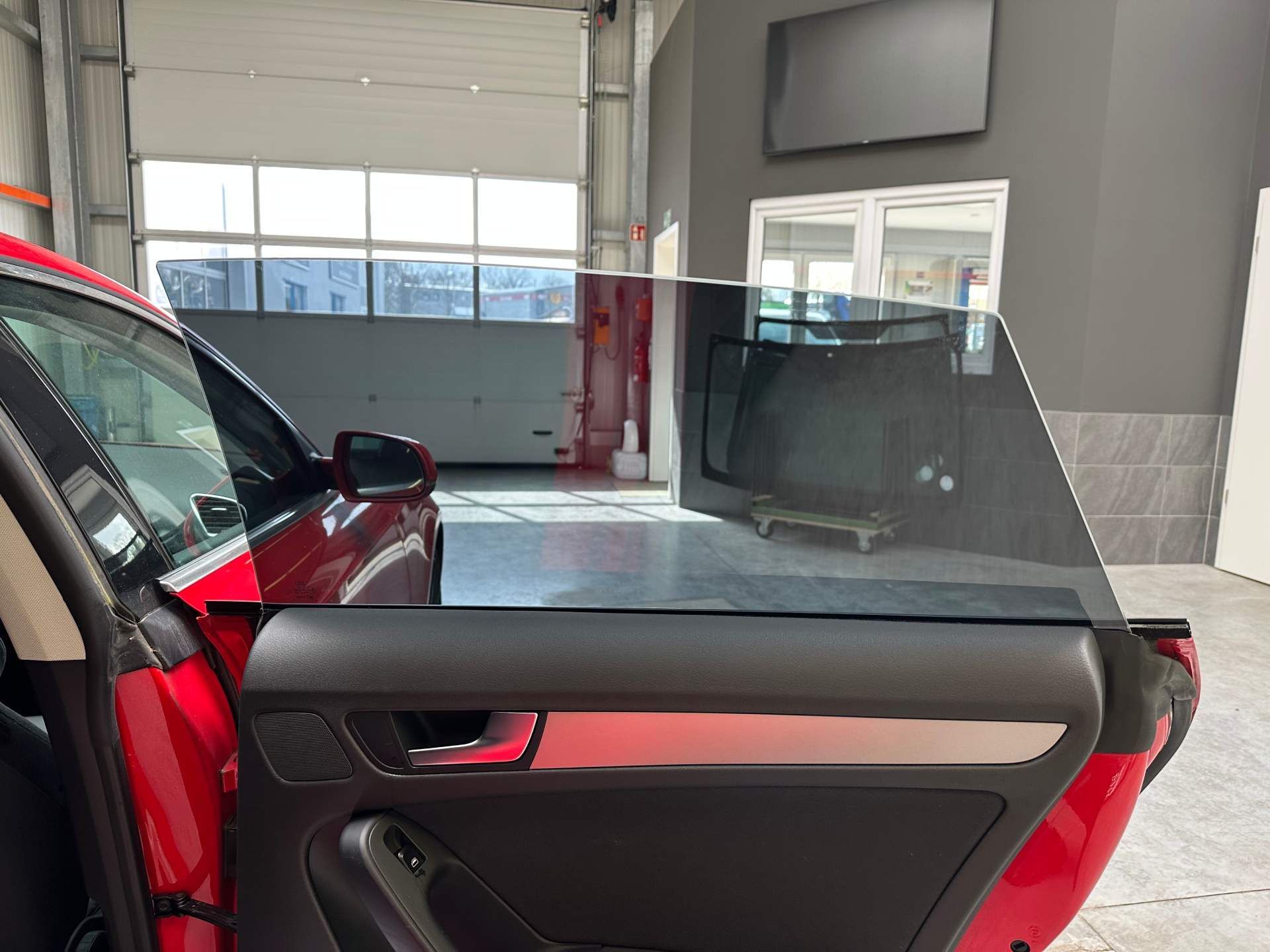 Ein rotes Auto steht mit geöffneter Tür in einer Garage