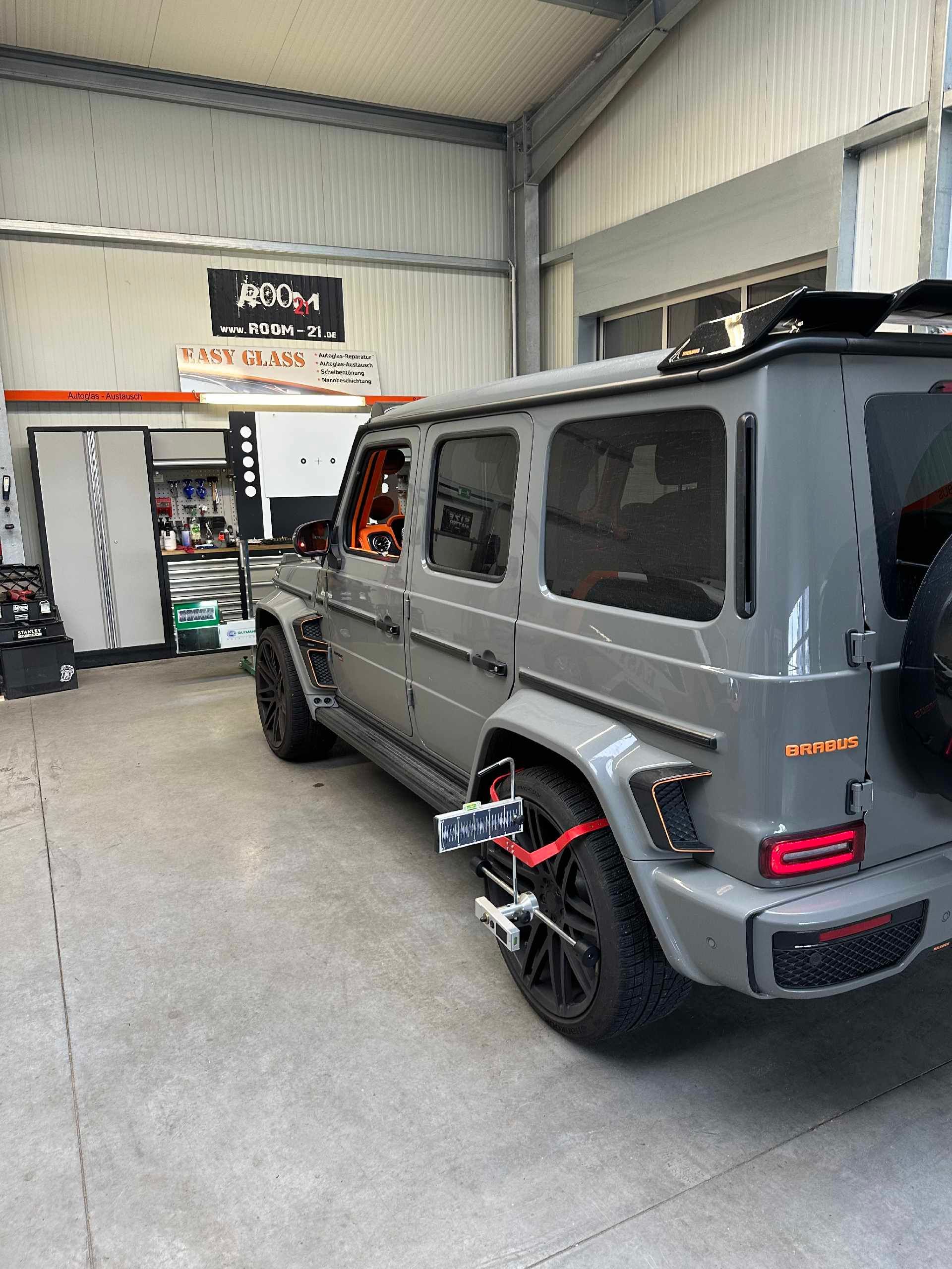 Ein grauer Mercedes Benz G63 steht in einer Garage.
