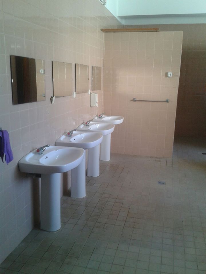 Un baño con una fila de lavabos y espejos.