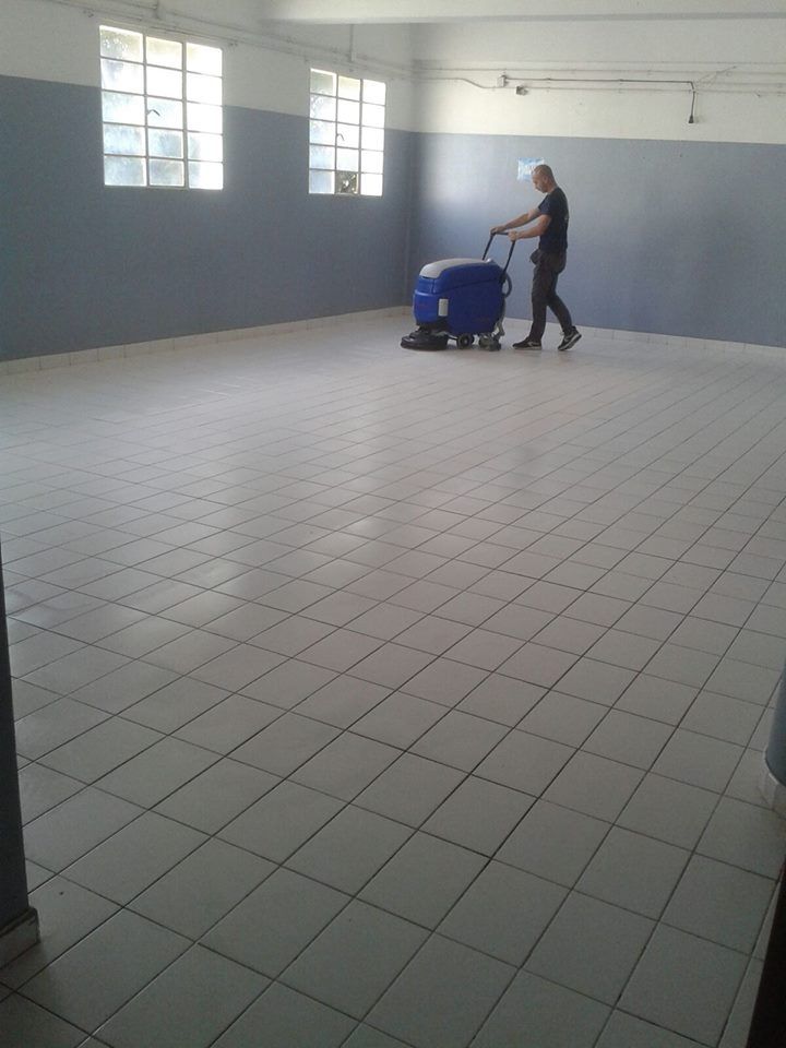 Un hombre está limpiando un piso de baldosas con una máquina.