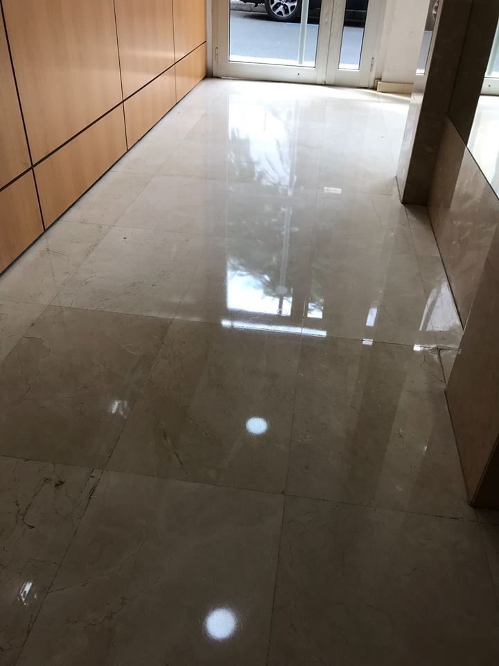 Un pasillo con suelo de mármol y puerta de cristal.