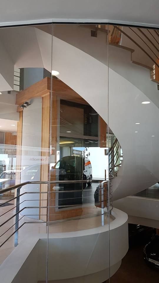 Un coche está aparcado en un garaje detrás de una pared de cristal.