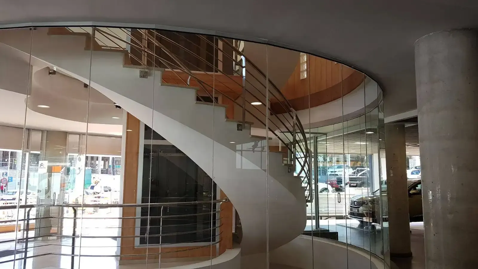 Una escalera de caracol en un edificio con barandilla de cristal.