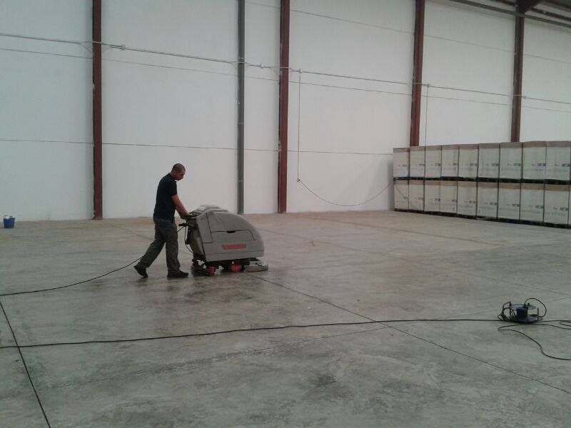 Un hombre está usando una máquina para limpiar un piso de concreto.