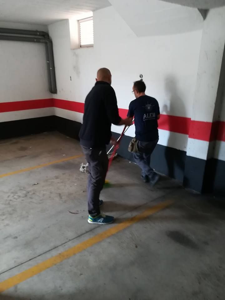Dos hombres están parados en un estacionamiento y uno de ellos lleva una camiseta que dice