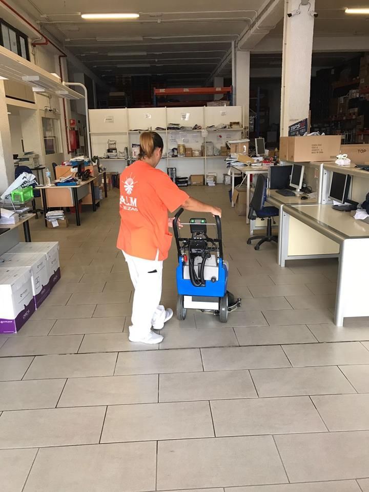 Una mujer está limpiando el suelo de una oficina con una aspiradora.
