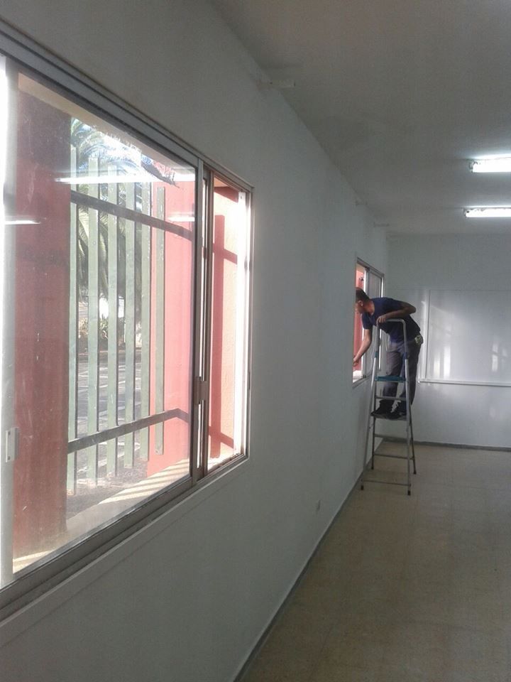 Un hombre está parado en una escalera en un pasillo al lado de una ventana.