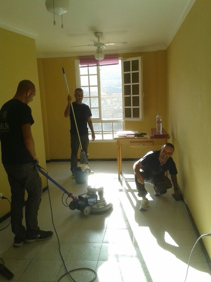 Tres hombres están limpiando una habitación con una aspiradora.