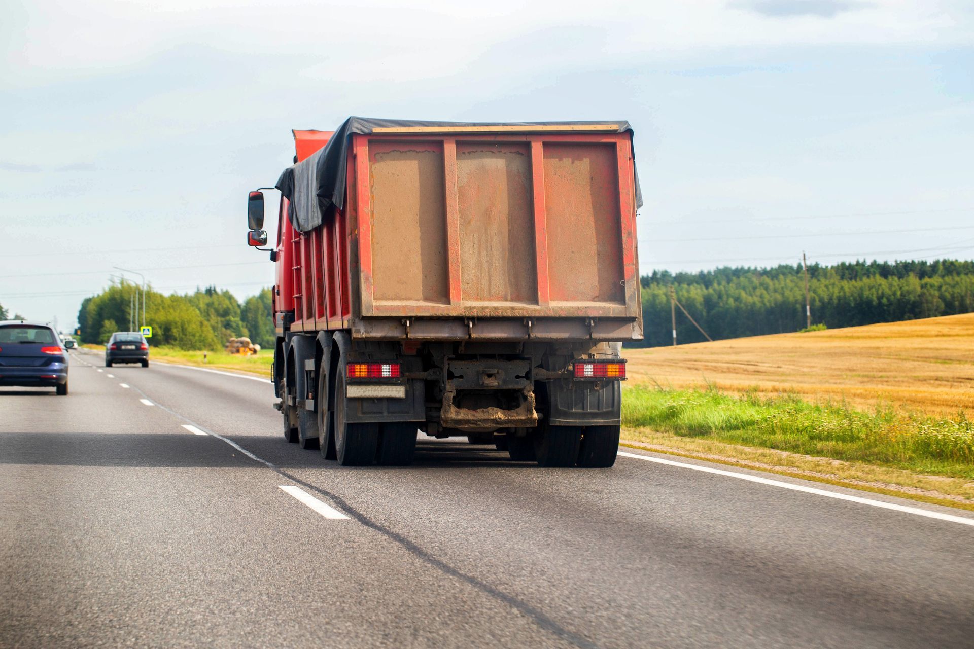 Camion à benne basculante rouge sur l'autoroute, transportant une charge.