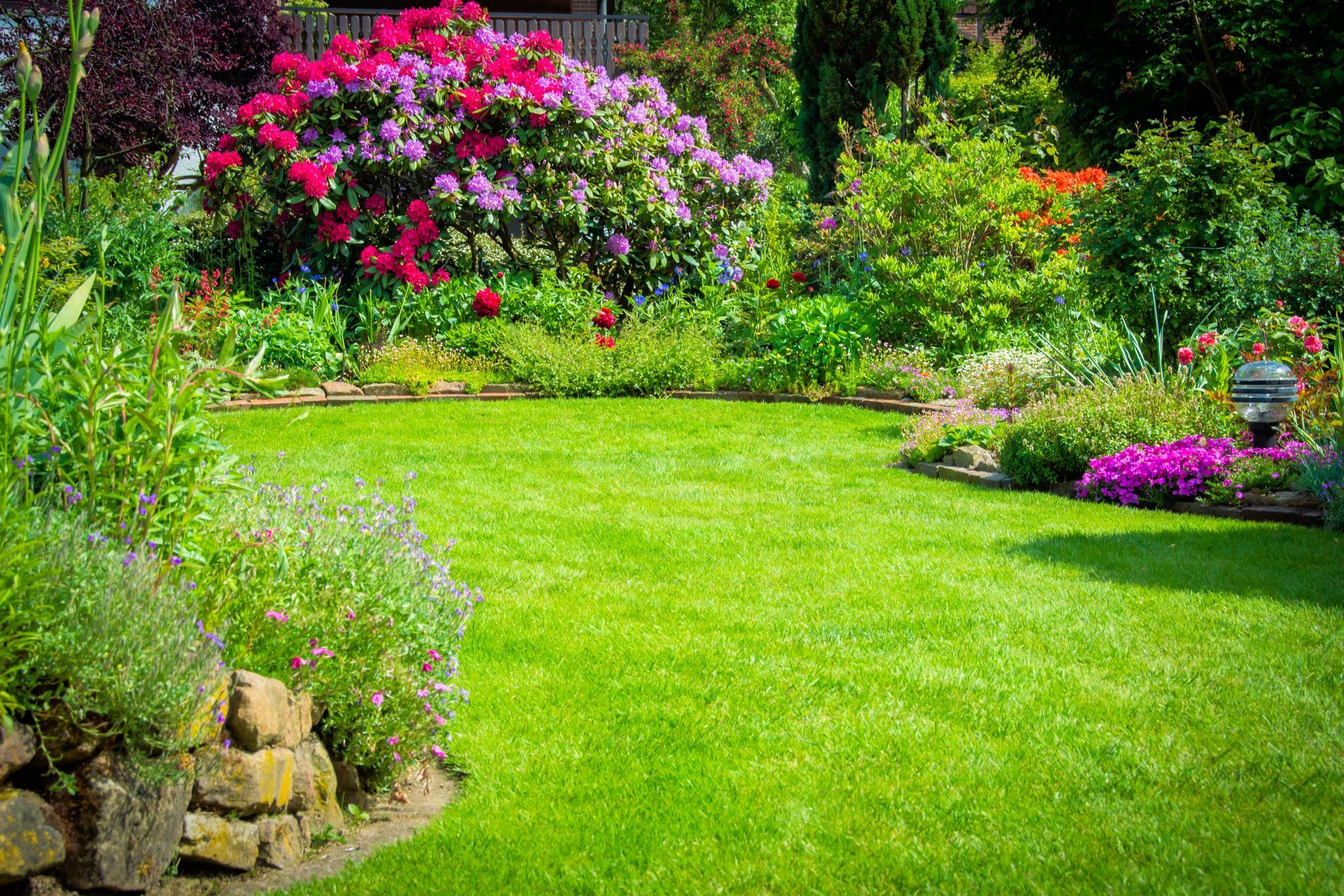 Jardin luxuriant avec pelouse d'un vert éclatant, fleurs colorées et arbustes denses en fleurs