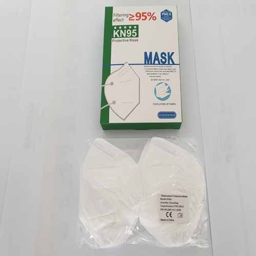 Eine Schachtel mit KN95-Masken steht neben einer Tüte mit Masken auf einem Tisch.