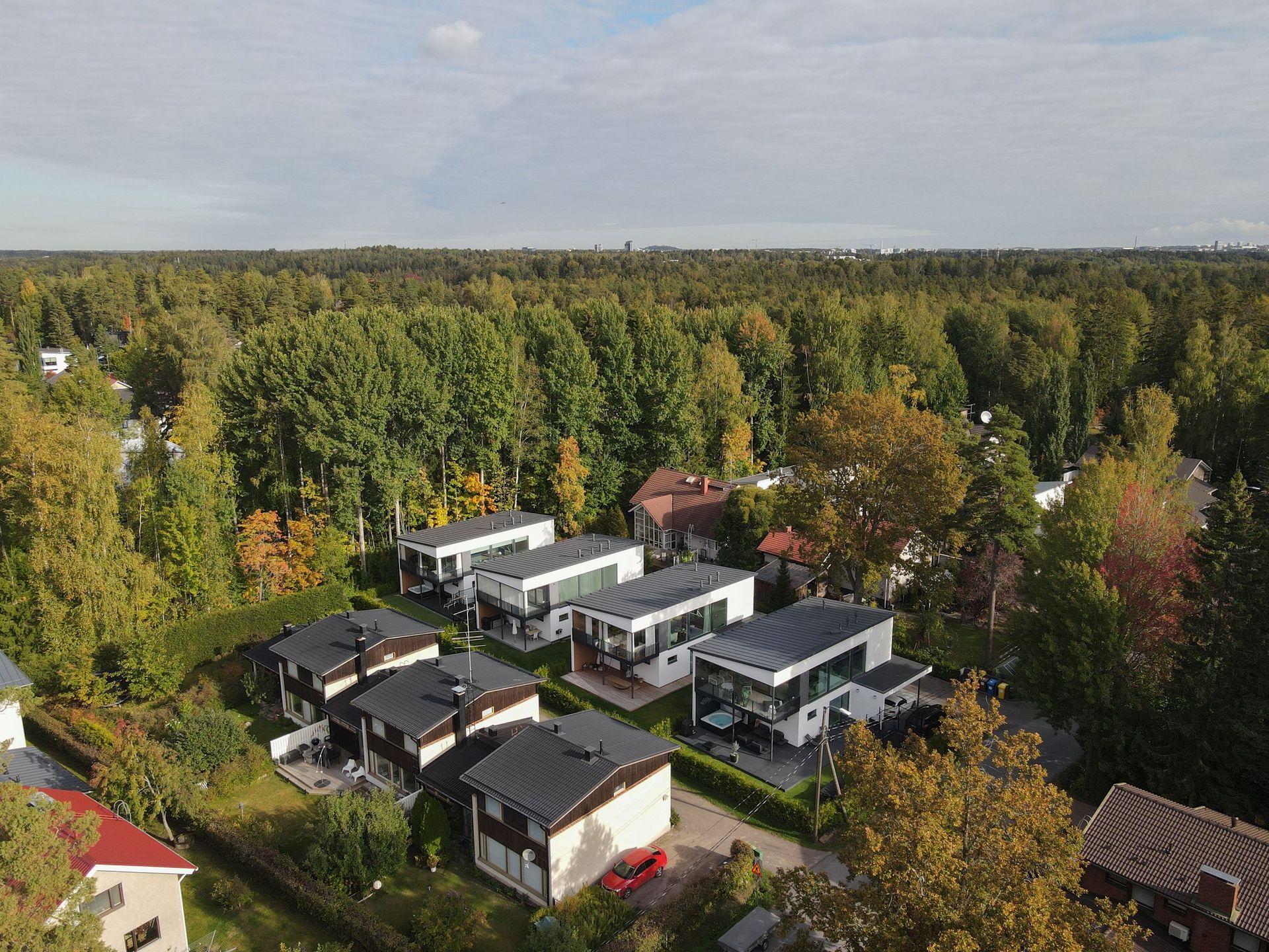 Modernit valkoiset talot sijaitsevat tiheiden vihreiden puiden keskellä hiljaisella metsäisellä alueella