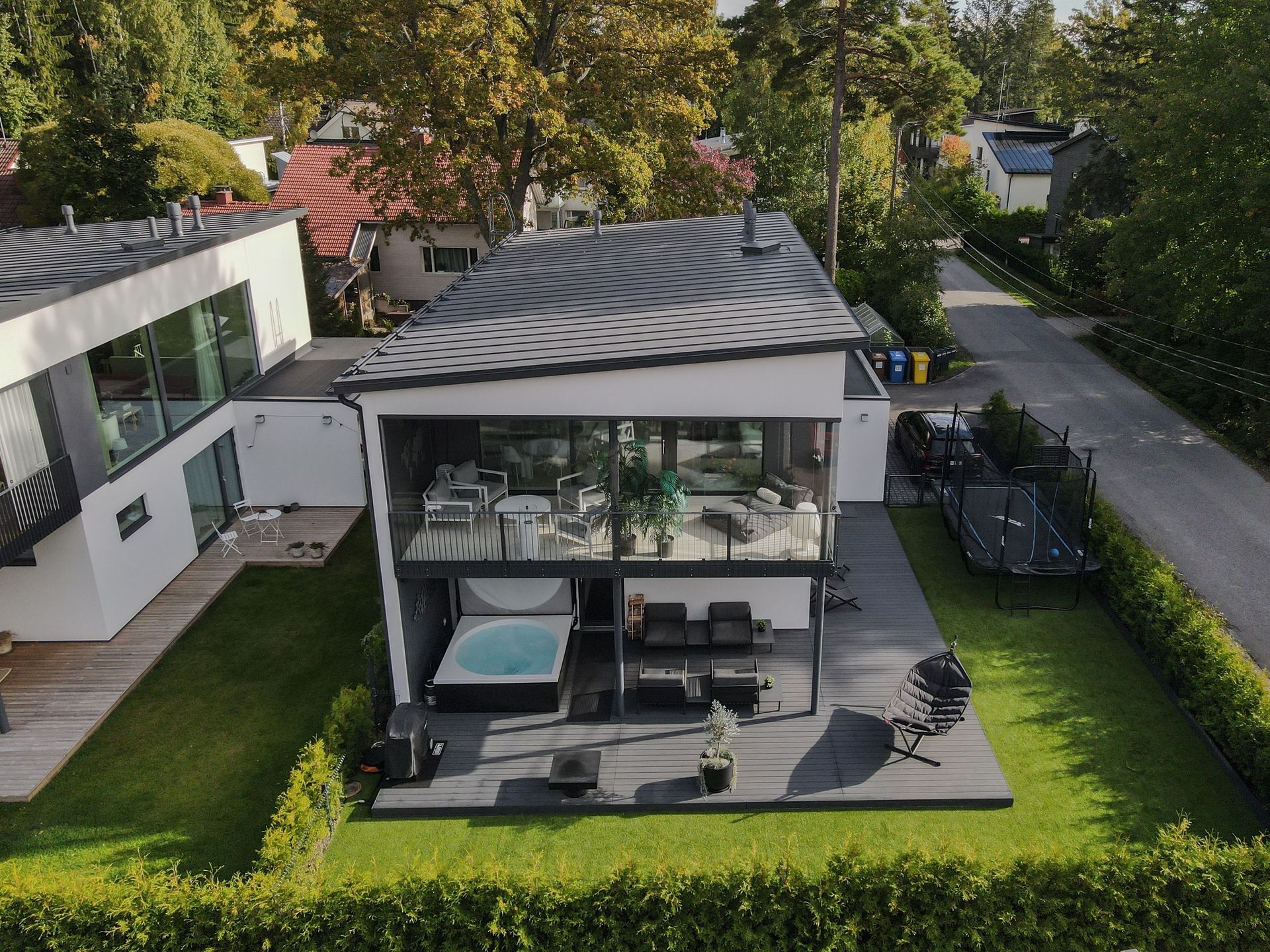 Moderni kaksikerroksinen takapihan patio pergolalla, ulkoistuimilla ja ympäröivällä vihreällä nurmikolla ja pensasaidoilla