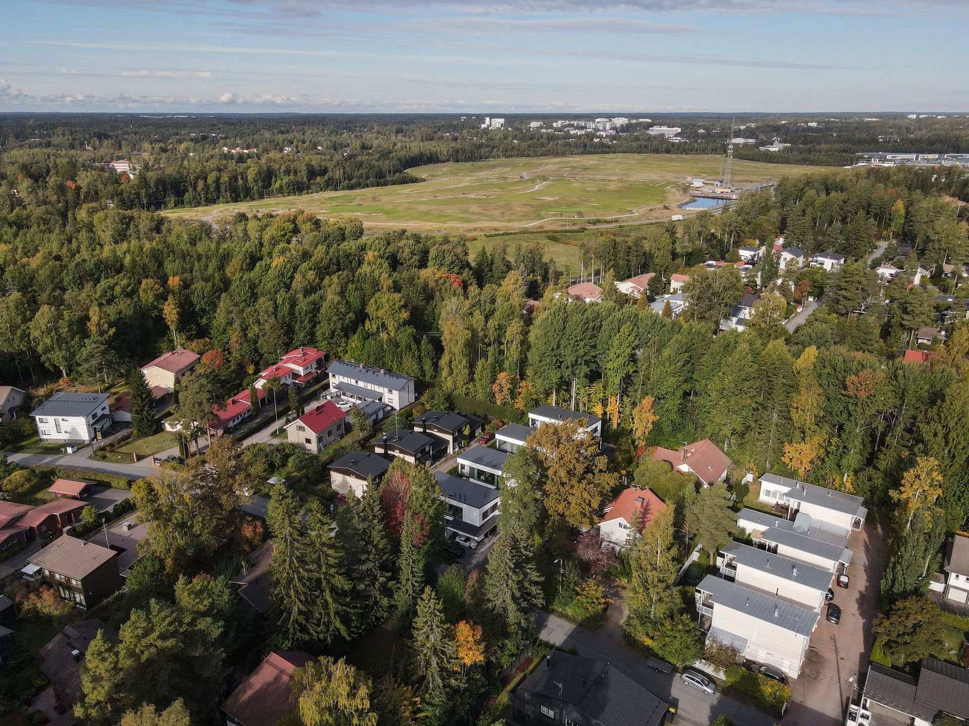 Ilmakuva metsäisestä naapurustosta avoimien peltojen vieressä kirkkaan taivaan alla