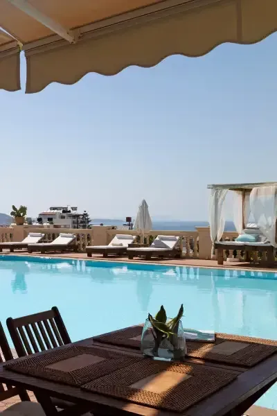 Une piscine sur le toit avec des chaises longues, une cabane et une table dressée sous un auvent rétractable, vue sur l'océan.