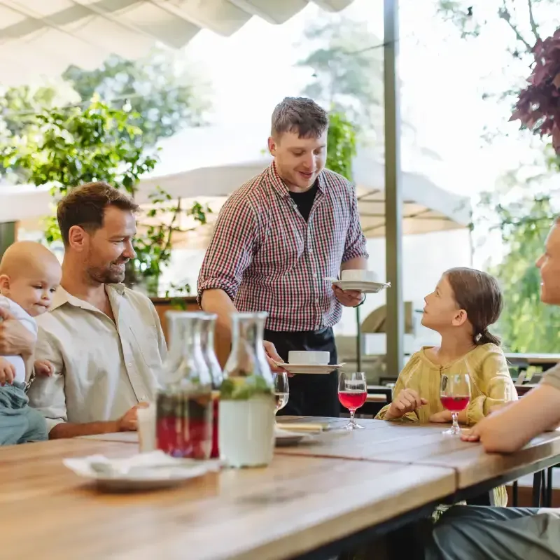 Des adultes et des enfants autour d'une table se faisant servir par un homme