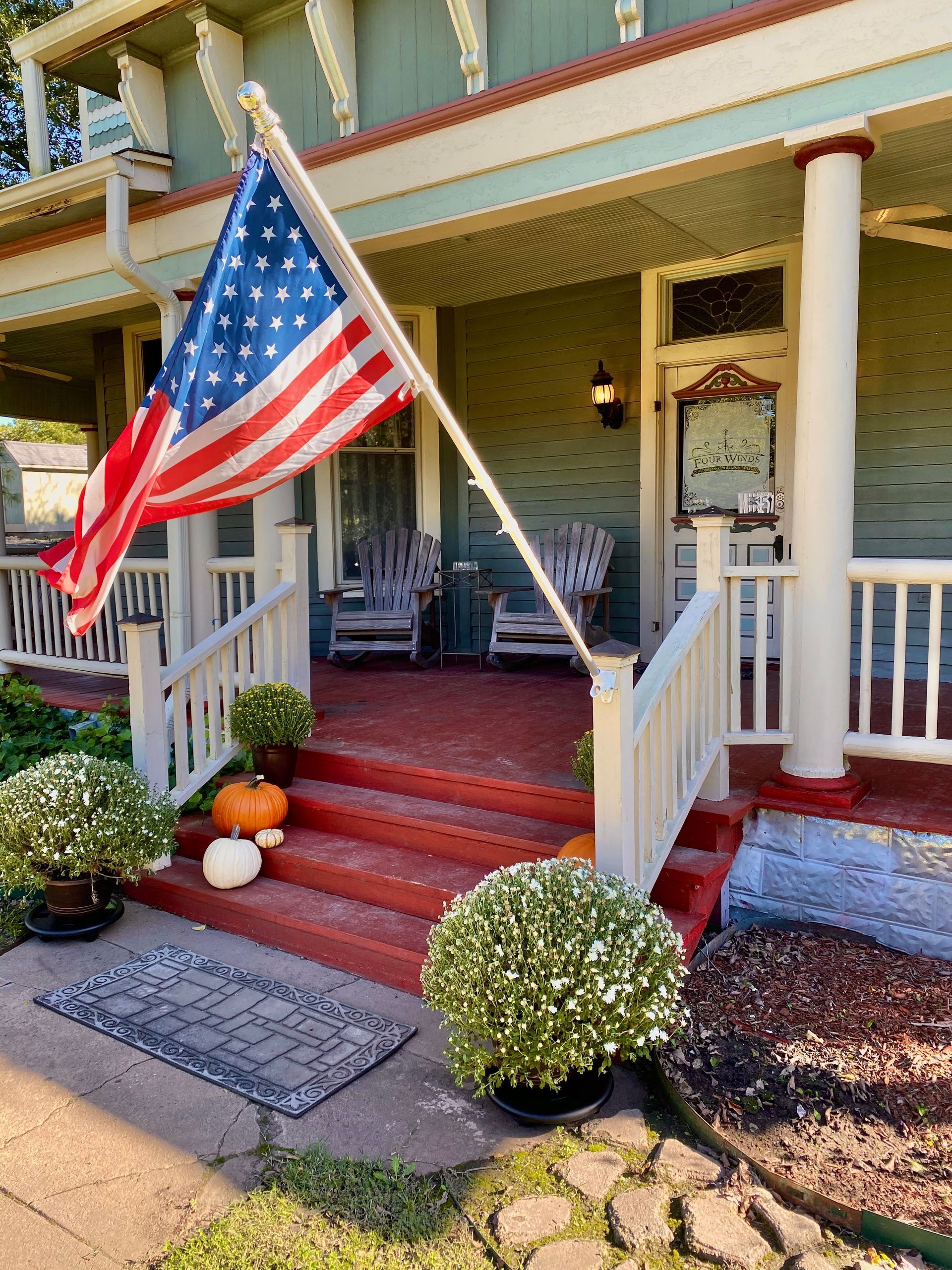 An american flag is flying on the porch of a house.