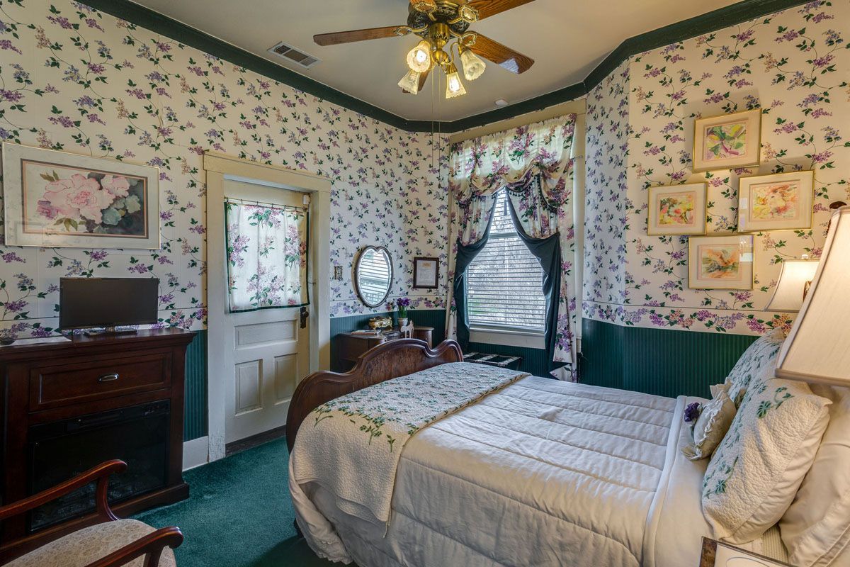 A bedroom with a king size bed , a ceiling fan , a chair , and a television.