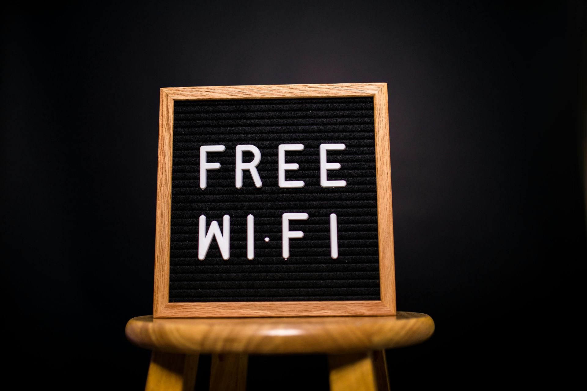 A sign that says free wi-fi is sitting on a wooden stool.