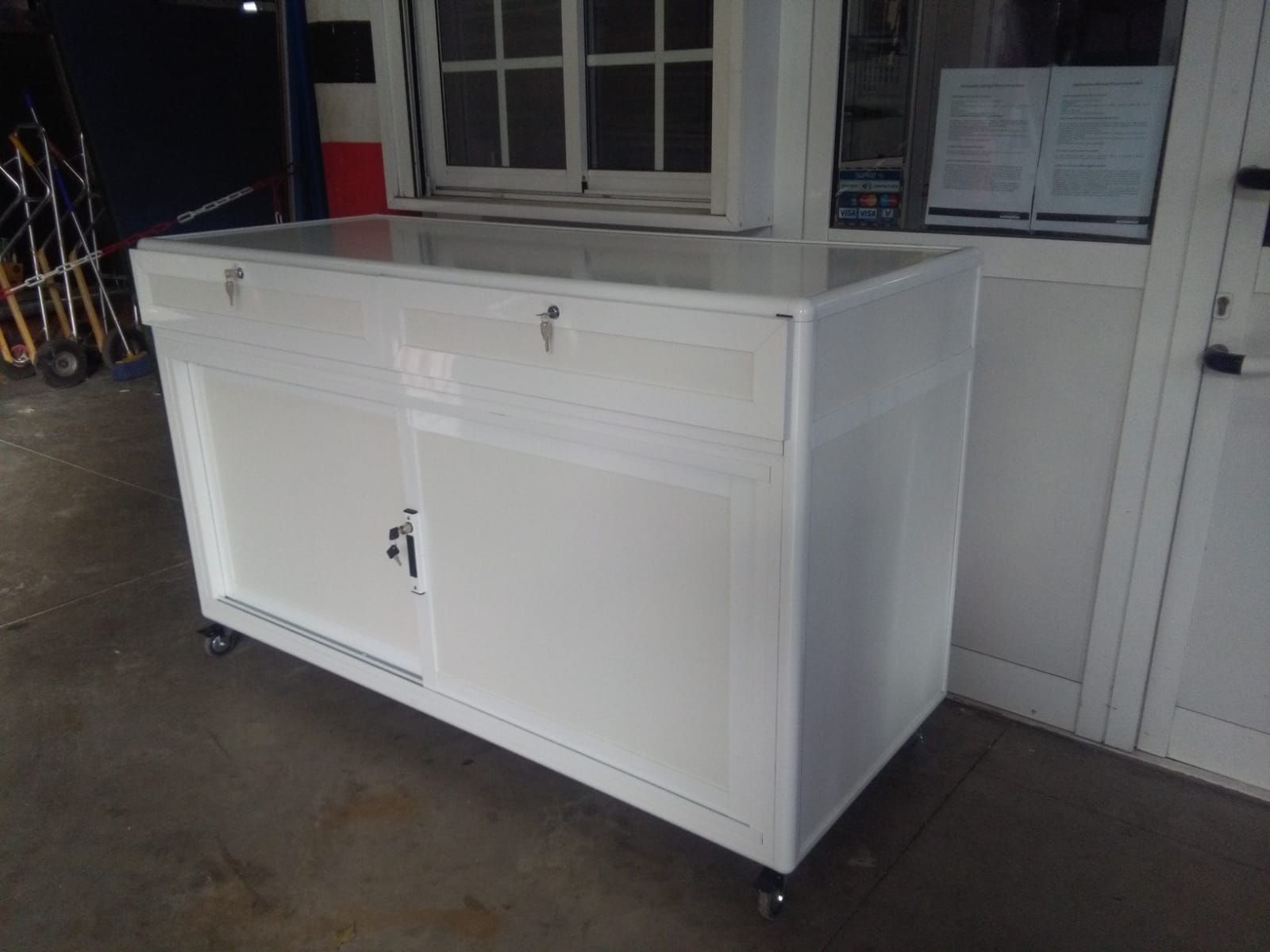 Un armario blanco con dos cajones y dos puertas está situado delante de una ventana.