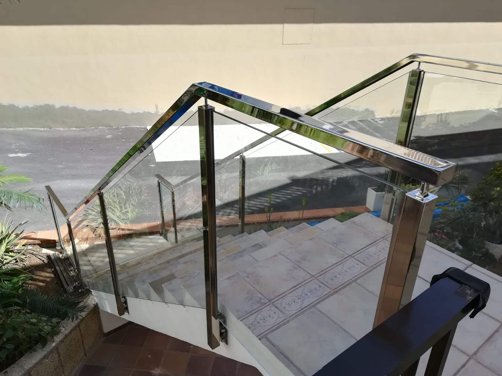 Una escalera con barandilla de cristal y vista al mar.